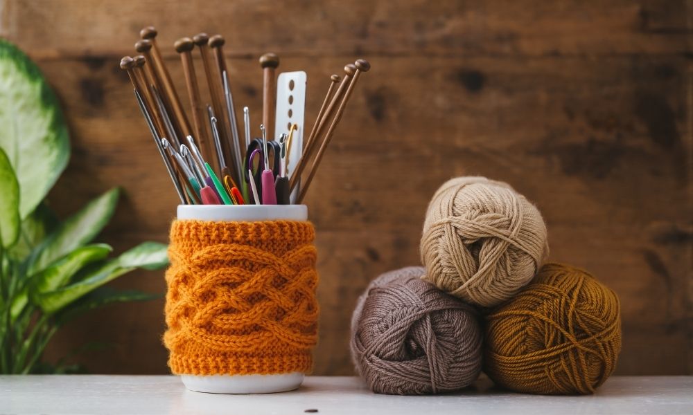Women's hobby. Crochet and knitting. Yarns in basket with crochet hooks  Multiple crocheting tools, crocheting supplies. Stock Photo